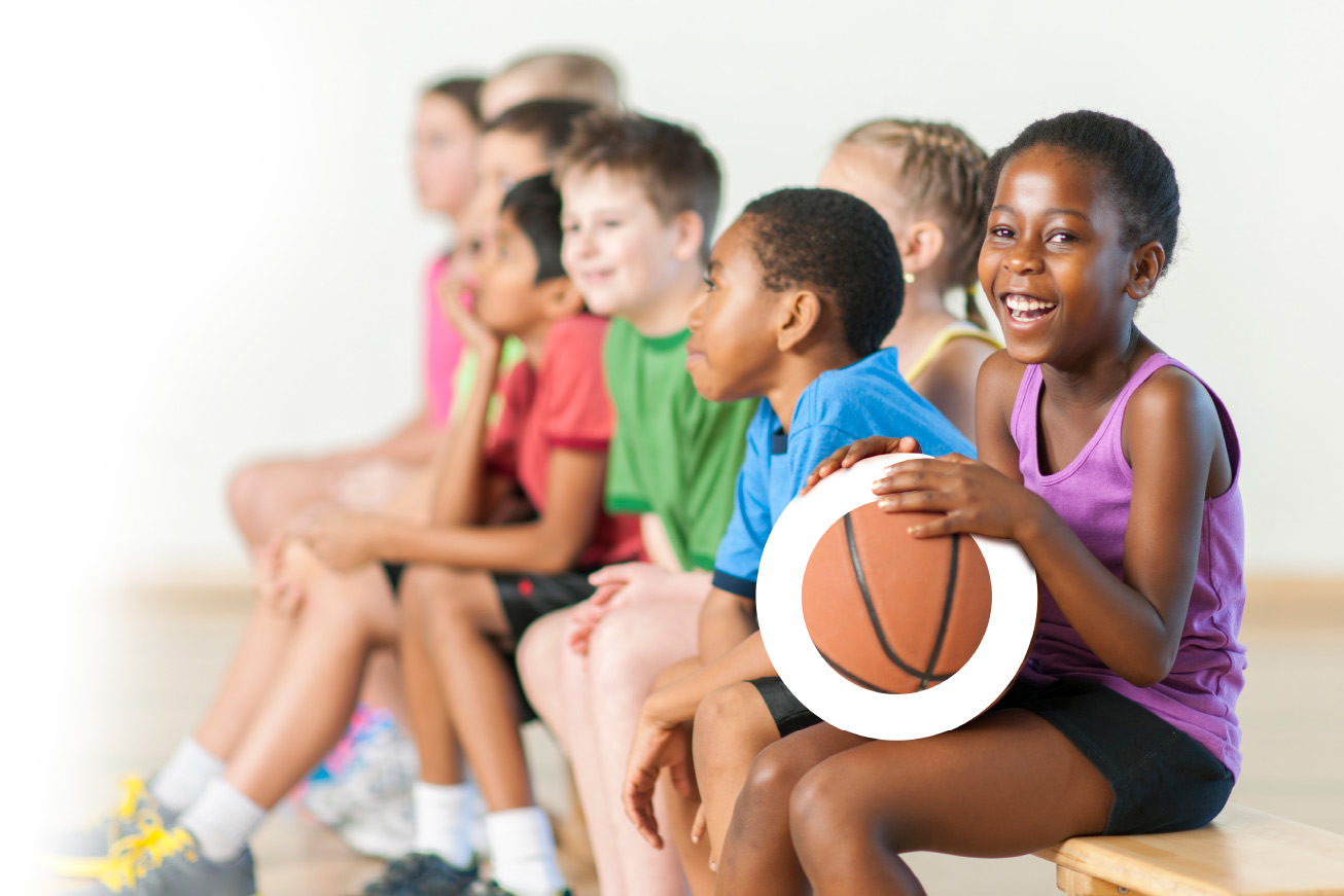 kids ina gym smiling holding a basketball