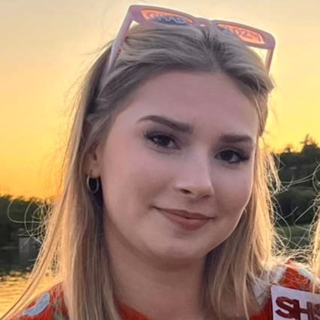 Audrey Godbout smiles in front of a beautiful sunset.